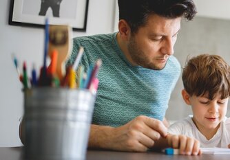 Vater hilft Jungen bei Hausaufgaben