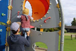 Ein Väter hält sein Kind am Klettergerüst auf dem Spielplatz fest